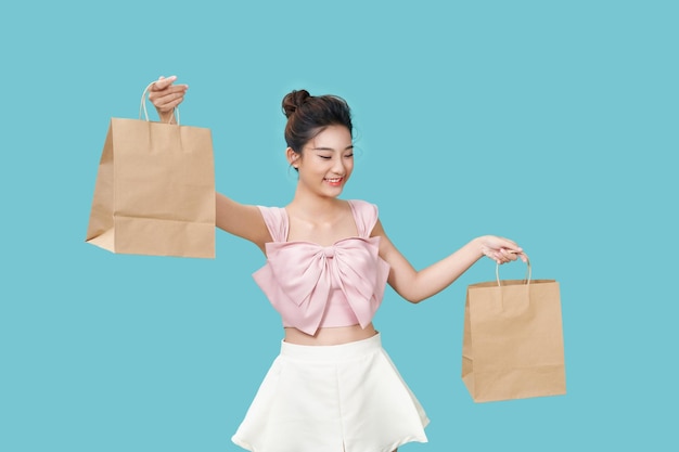 A young pretty girl shows off a large brown paper bag on a cyan background