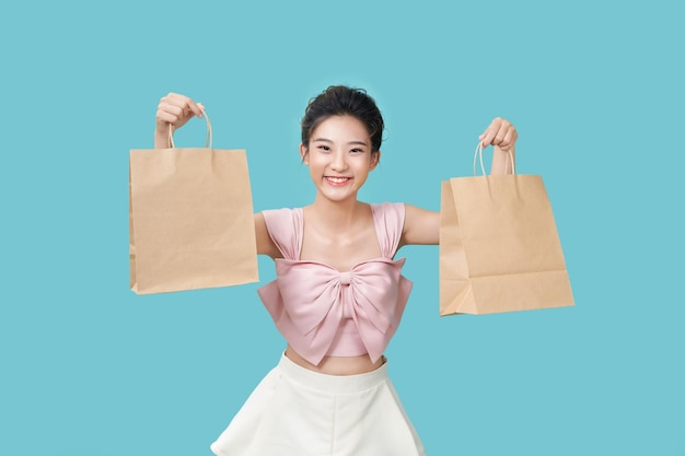 A young pretty girl shows off a large brown paper bag on a cyan background