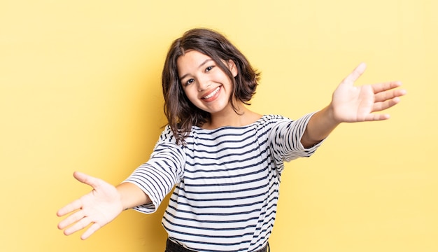 Young pretty girl smiling cheerfully giving a warm, friendly, loving welcome hug, feeling happy and adorable