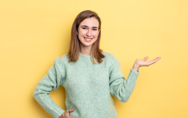 Young pretty girl smiling, feeling confident, successful and happy, showing concept or idea on copy space on the side