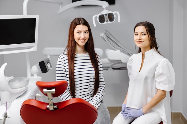 Young pretty girl talking to female dentist while sitting in chair in modern dental clinic