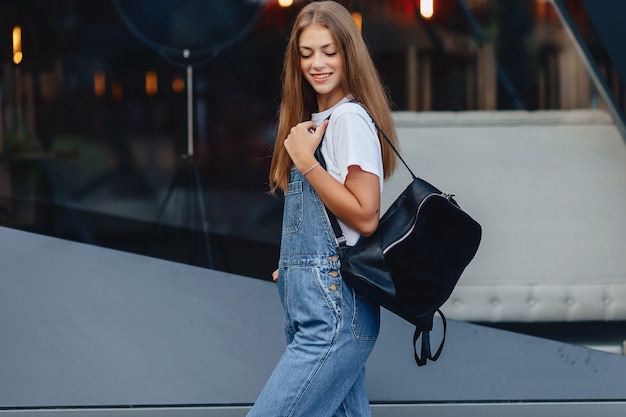 Молодая красивая девушка с портфельной прогулкой на улице возле здания
