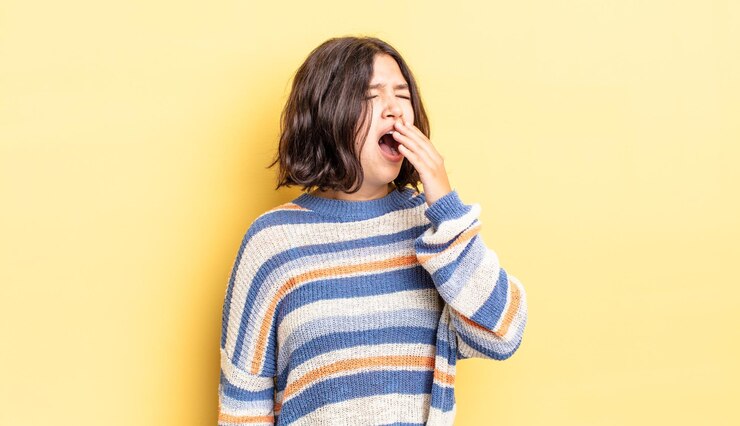 Photo 朝早くに怠惰にあくびをし、目を覚まし、眠く見え、疲れて退屈している若いかわいい女の子