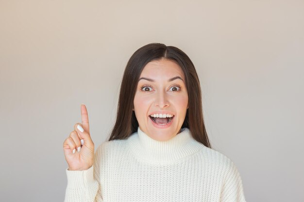 写真 ショッキングな幸せな顔をしている若いかなり幸せな女性が空の背景に指を上げています