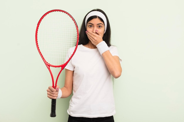 ショックを受けたテニスのコンセプトで手で口を覆う若いかなりヒスパニック系の女性