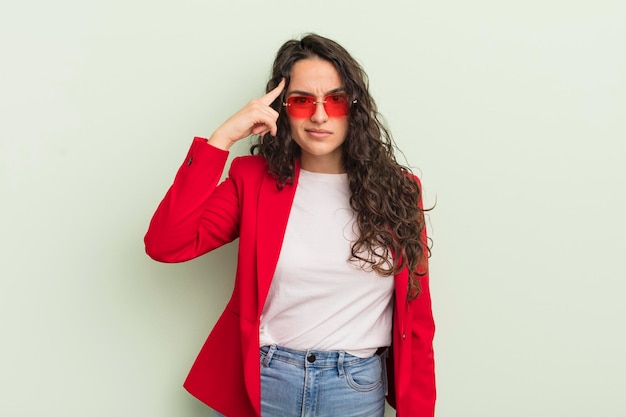 Young pretty hispanic woman feeling confused and puzzled showing you are insane cool businesswoman