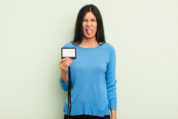 Young pretty hispanic woman feeling disgusted and irritated and tongue out accreditation pass id concept