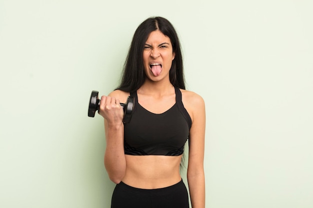 young pretty hispanic woman feeling disgusted and irritated and tongue out. fitness concept