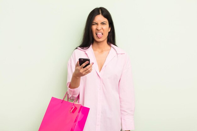 Young pretty hispanic woman feeling disgusted and irritated and tongue out shopping bags concept