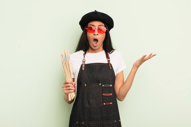 Young pretty hispanic woman feeling extremely shocked and surprised art student concept