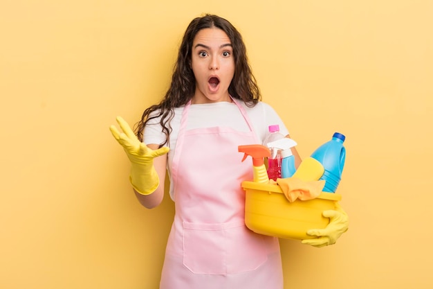 Young pretty hispanic woman feeling extremely shocked and surprised. housework an clean products concept