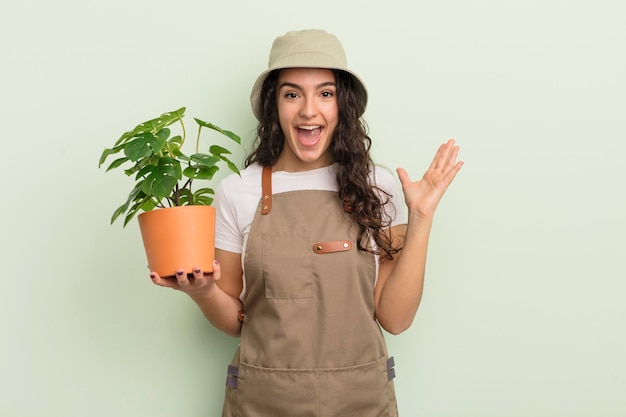 Young pretty hispanic woman feeling happy and astonished at something unbelievable farmer or gardener concept