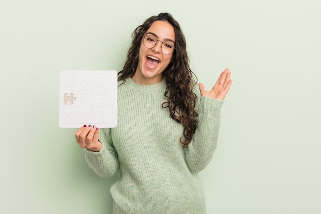 Young pretty hispanic woman feeling happy and astonished at something unbelievable puzzle concept