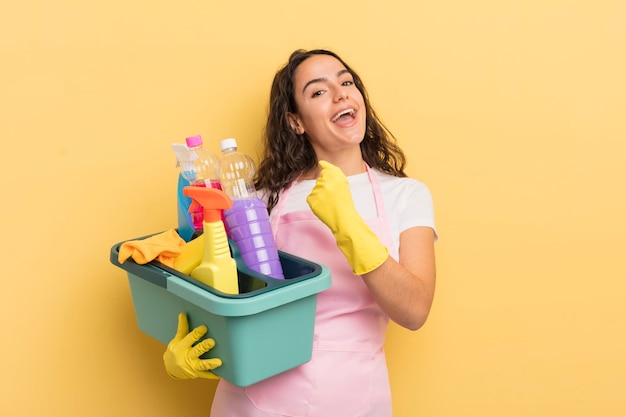 Young pretty hispanic woman feeling happy and facing a\
challenge or celebrating. housework an clean products concept
