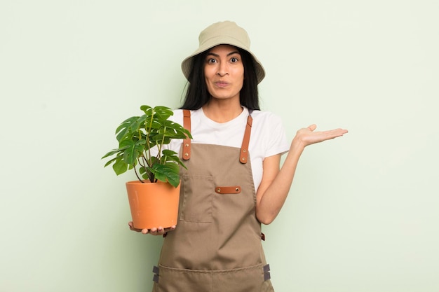 young pretty hispanic woman feeling puzzled and confused and doubting farmer or gardener concept