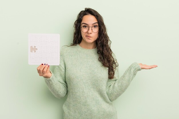 Foto giovane donna abbastanza ispanica che si sente perplessa e confusa e dubita del concetto di puzzle