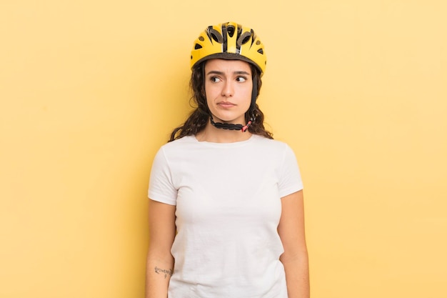 Молодая симпатичная латиноамериканка чувствует себя грустной, расстроенной или злой и смотрит в сторону концепции велосипеда