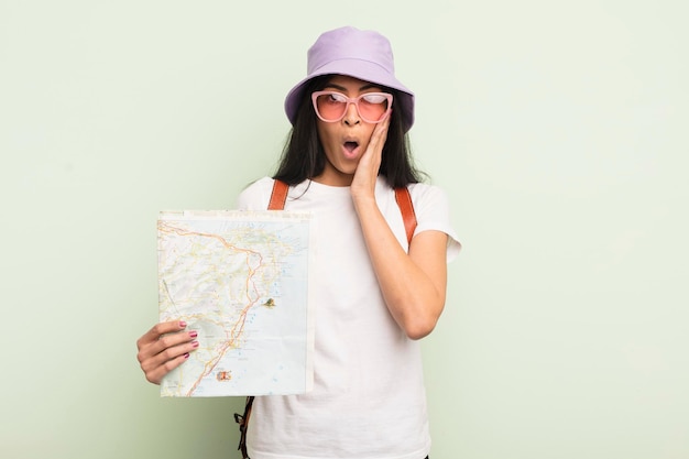 Young pretty hispanic woman feeling shocked and scared tourist and map concept