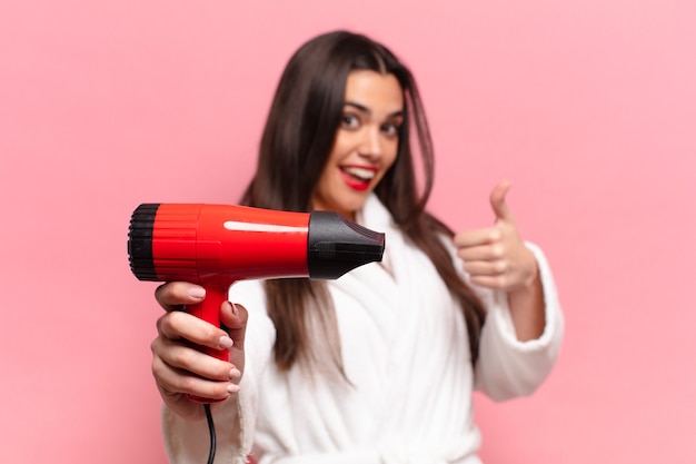 若いかなりヒスパニック系の女性。幸せで驚きの表情。ヘアドライヤーのコンセプト