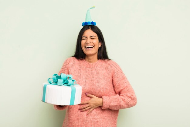 Young pretty hispanic woman laughing out loud at some hilarious joke birthday cake concept