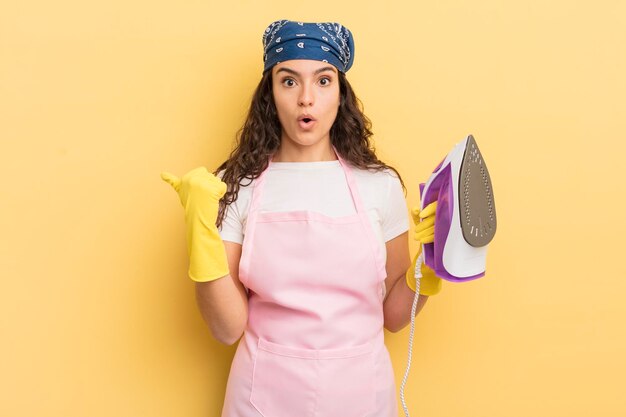 Young pretty hispanic woman looking astonished in disbelief iron and clothes concept