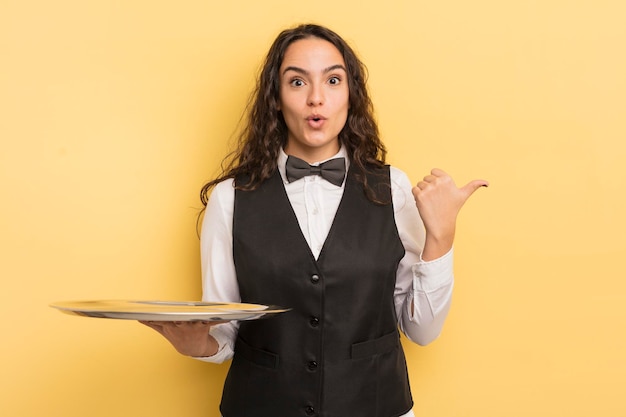 Young pretty hispanic woman looking astonished in disbelief. waiter and tray concept