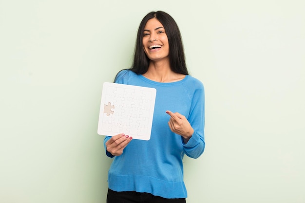 Young pretty hispanic woman looking excited and surprised pointing to the side puzzle concept