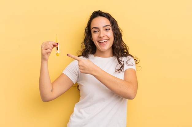 Young pretty hispanic woman looking excited and surprised pointing to the side thermometer concept