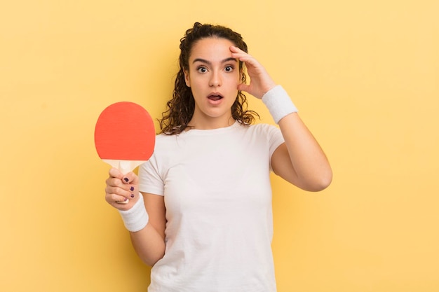 Young pretty hispanic woman looking happy astonished and surprised ping pong concept