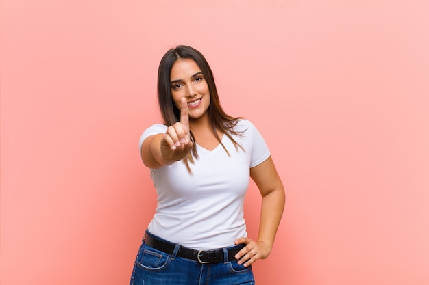 Giovane bella donna ispanica che sembra stressata, stanca e frustrata, asciuga il sudore dalla fronte, si sente senza speranza ed esausta contro il muro rosa