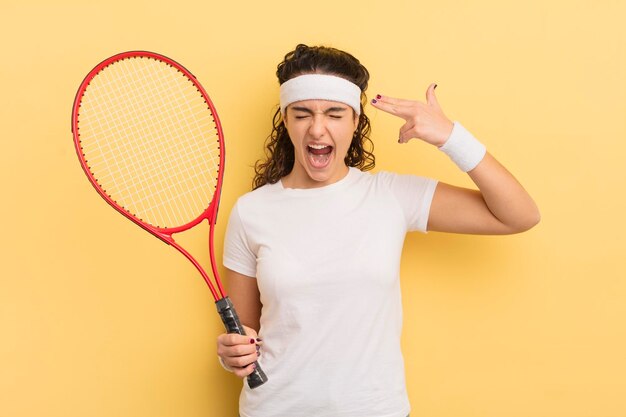 young pretty hispanic woman looking unhappy and stressed, suicide gesture making gun sign. tennis concept