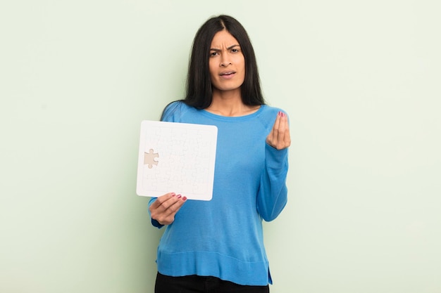 Young pretty hispanic woman making capice or money gesture telling you to pay puzzle concept