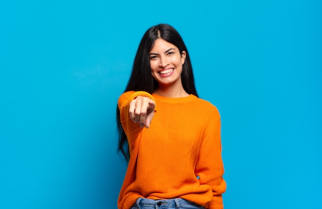 Young pretty hispanic woman pointing at camera with a satisfied, confident, friendly smile, choosing you