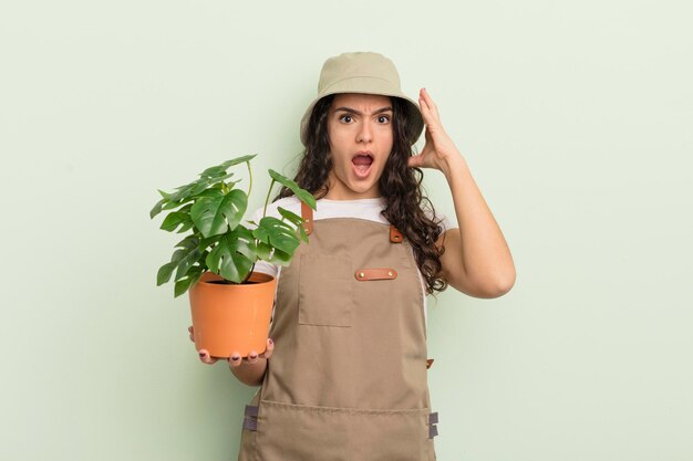 young pretty hispanic woman screaming with hands up in the air. farmer or gardener concept