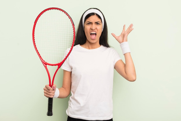 Young pretty hispanic woman screaming with hands up in the air tennis concept