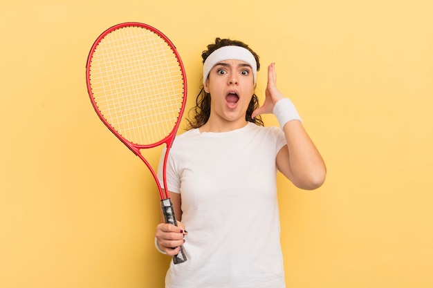 Young pretty hispanic woman screaming with hands up in the air tennis concept