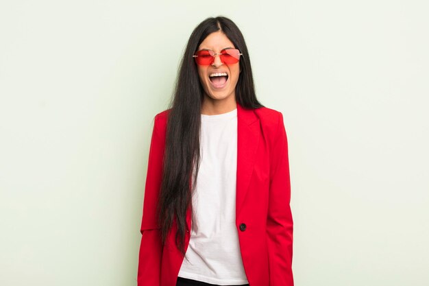 Young pretty hispanic woman shouting aggressively looking very angry businesswoman concept