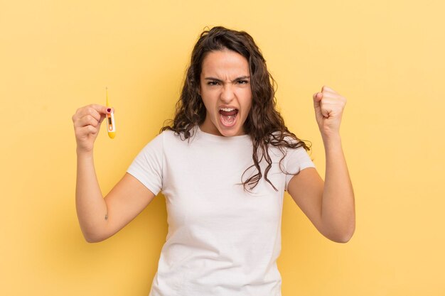 Young pretty hispanic woman shouting aggressively with an angry expression thermometer concept