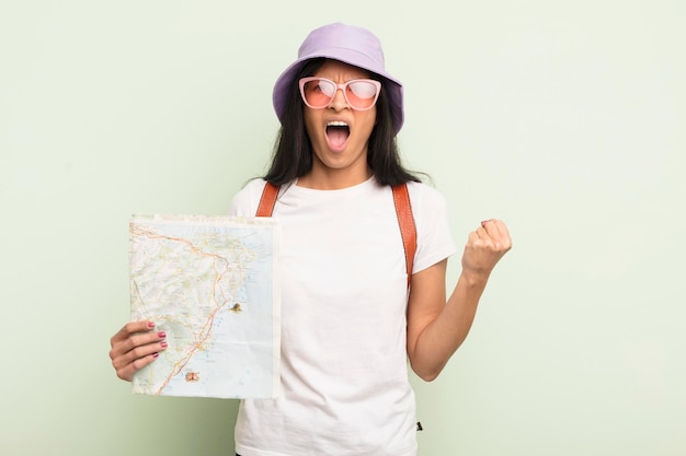 Young pretty hispanic woman shouting aggressively with an angry expression tourist and map concept