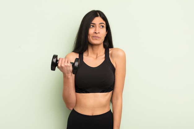 Young pretty hispanic woman shrugging feeling confused and uncertain fitness concept