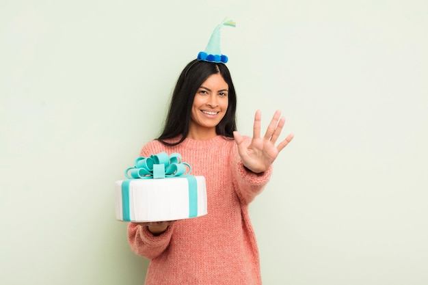 Young pretty hispanic woman smiling and looking friendly showing number five birthday cake concept