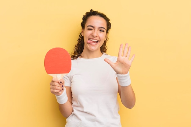 Young pretty hispanic woman smiling and looking friendly showing number five ping pong concept