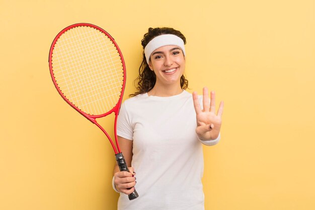 Young pretty hispanic woman smiling and looking friendly showing number four tennis concept