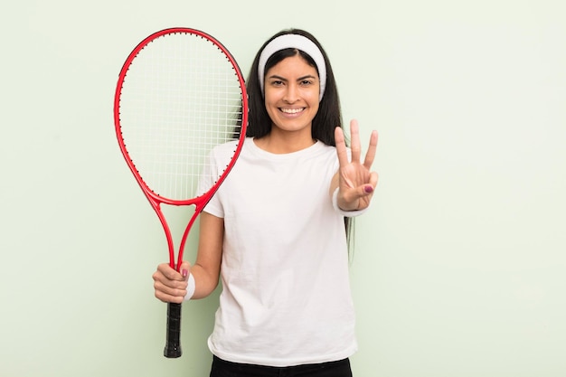 Young pretty hispanic woman smiling and looking friendly showing number three tennis concept