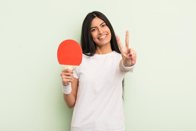 若いかなりヒスパニック系の女性の笑顔と幸せなジェスチャーの勝利または平和ピンポンの概念を探しています