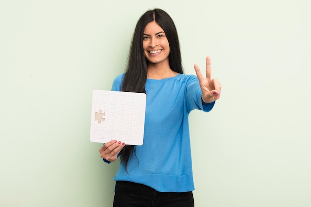 Young pretty hispanic woman smiling and looking happy gesturing victory or peace puzzle concept