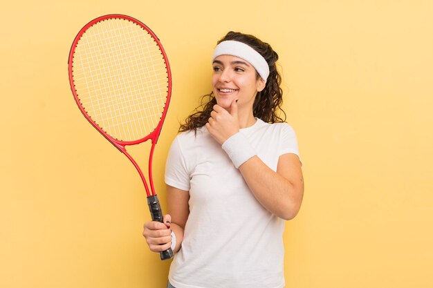 Young pretty hispanic woman smiling with a happy confident expression with hand on chin tennis concept