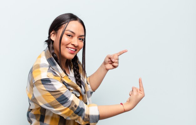 Young pretty hispanic woman with a copy space against isolated wall