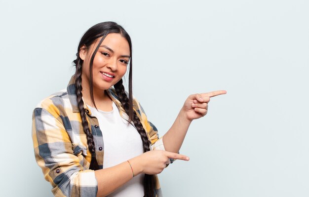 Young pretty hispanic woman with a copy space against isolated wall