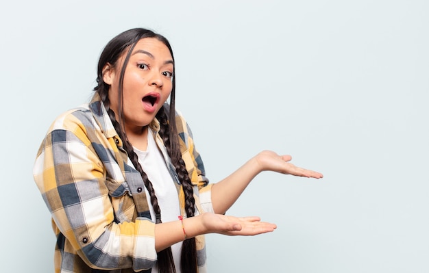 Young pretty hispanic woman with a copy space against isolated wall